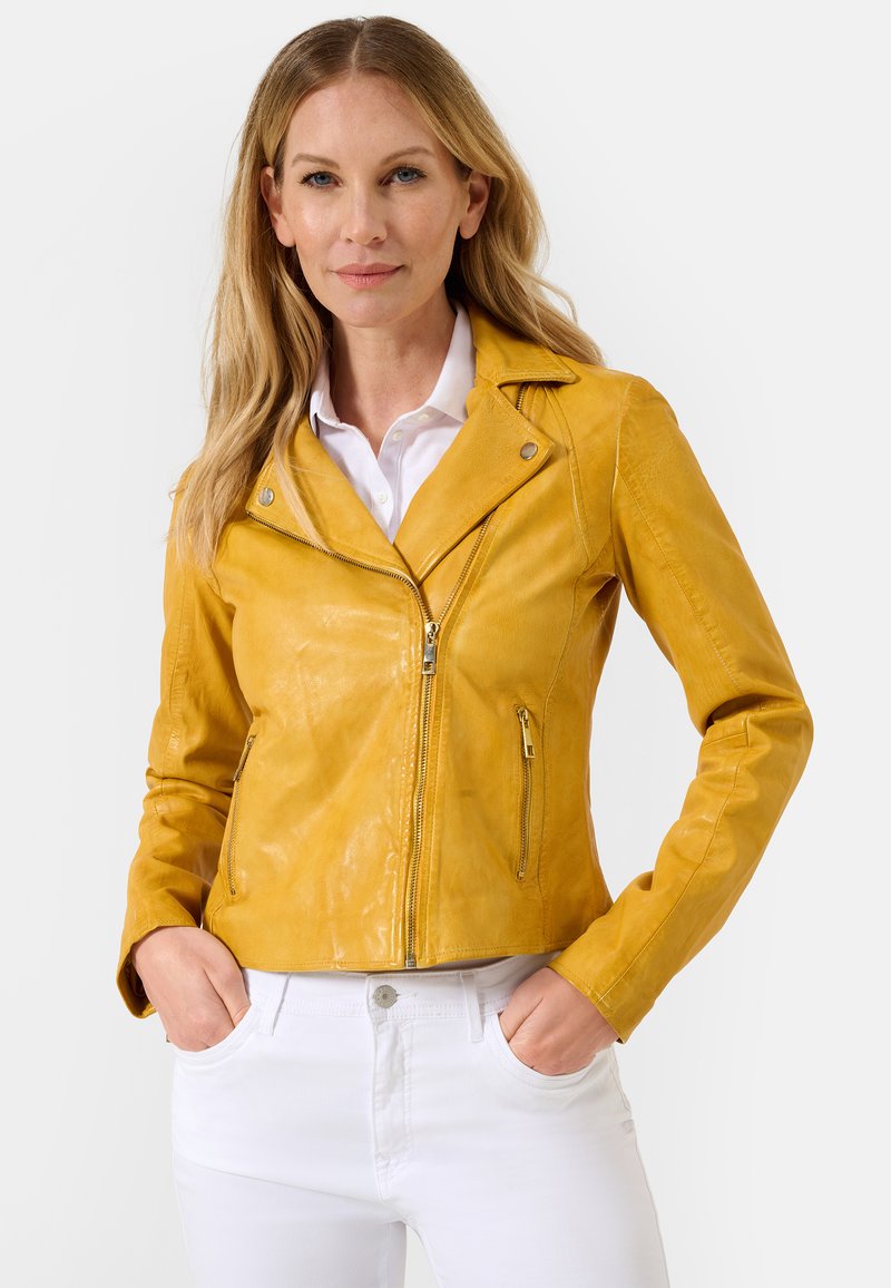 Gele leren motorjack met een slim fit ontwerp, ritssluiting en accenten van zilver, gecombineerd met witte broek.