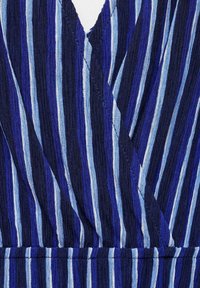 Le tissu à rayures bleues présente des lignes de différentes largeurs en bleu foncé et bleu clair avec une texture froissée. Le design comprend un col en V et une taille froncée.