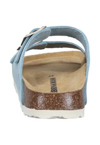 Jasnoniebieska zamszowa sandałka z korkową wkładką i białą gumową podeszwą. Posiada dwa górne paski oraz metalową klamrę do regulacji.