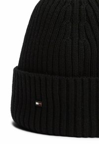 Beanie a costine nera con risvolto, caratterizzato da un piccolo logo rettangolare in rosso, bianco e blu vicino al bordo.
