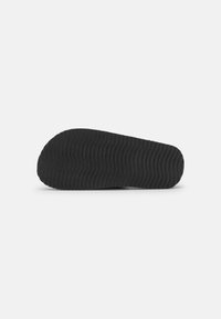 Black rubber shoe sole with a wavy textured pattern, rounded front edge, and smooth finish.
