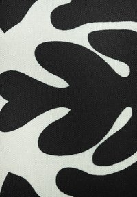 Schwarzer und weißer Stoff mit einem abstrakten, unregelmäßigen Muster, das große, fließende Formen auf einem strukturierten Hintergrund zeigt.