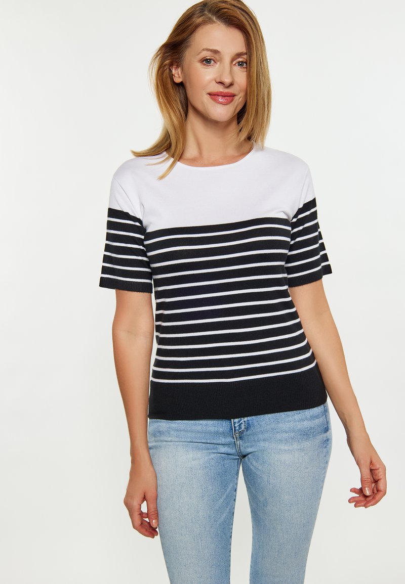 Tricou tricotat cu mânecă scurtă, în dungi albastre și albe, cu guler rotund și textură ribbată. Asortat cu blugi de culoare albastră deschisă.