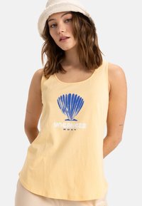 Débardeur en coton jaune avec un graphique de coquillage bleu et un texte blanc qui dit "VACANCES ROXY." Encolure arrondie et coupe décontractée.