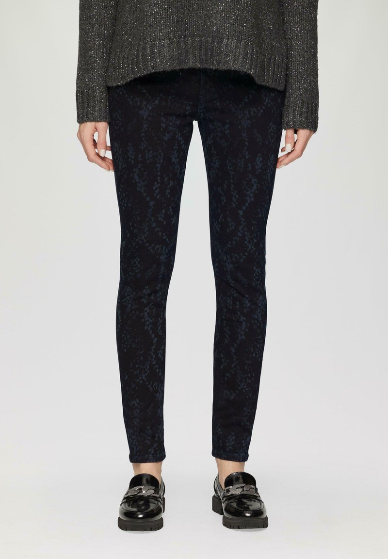 Ciemnoniebieskie, wzorzyste rurki z eleganckim krojem, charakteryzujące się subtelnym, teksturowanym wzorem oraz wykończeniem u dołu, zestawione z błyszczącymi czarnymi mokasynami.