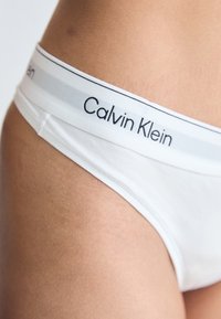 Bijele pamučne gaćice s Calvin Klein logotipom na elastičnom pojasu s nijansama sive, glatke teksture i klasičnim krojem.