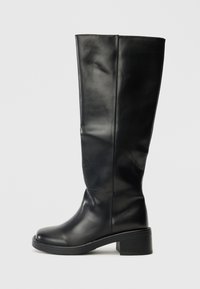 Bottes noires montantes en cuir lisse, avec un bout rond et un talon large, au design simple sans quincaillerie visible.
