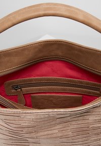 Borsa beige in pelle texturizzata con interno marrone liscio e fodera rosso acceso, con tasca con cerniera e dettaglio logo in rilievo.