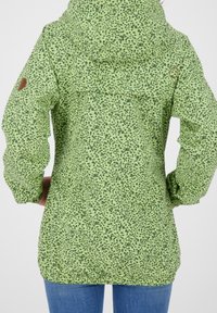 Zielona kurtka w wzory z kapturem, z plamkami w ciemnozielonym kolorze, elastycznymi mankietami i małym logo na lewym ramieniu.