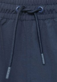 Shorts bleu marine en tissu texturé, dotés d'un cordon de serrage avec embouts en plastique et œillets renforcés. Finition lisse avec un léger aspect brillant.