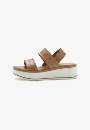 Brown leather platform sandal with two wide straps, elastic ankle band, white rubber sole, and subtle stitching details.