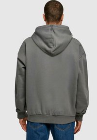 Grå hoodie med avslappnad passform, huva, räfflade ärmslut och midja. Slät textur utan synliga mönster eller hårdvarudetaljer.