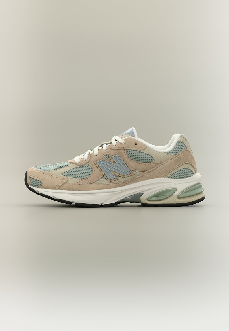 Baskets beige et vert clair avec lacets blancs, empiècements en mesh et daim, semelle rembourrée et logo "N" sur le côté.