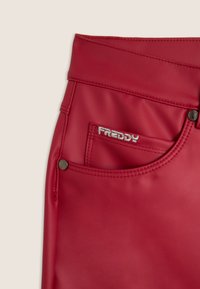 Pantaloni in pelle rossa con tasca anteriore e ricamo in argento "FREDDY" sulla tasca piccola, dotati di rivetti in metallo e cuciture dettagliate.