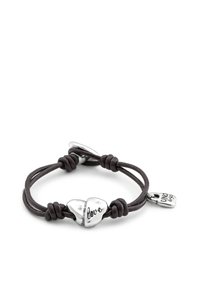 Pulsera de cuero con un dije doble corazón inscrito con la palabra "amor" y una pequeña etiqueta plateada. Color marrón oscuro, diseño simple con nudo.