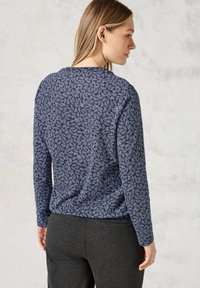 Marineblauwe lange mouw top met een wit abstract patroon, gemaakt van zachte stof. Het ontwerp heeft een ronde halslijn en een relaxed fit.