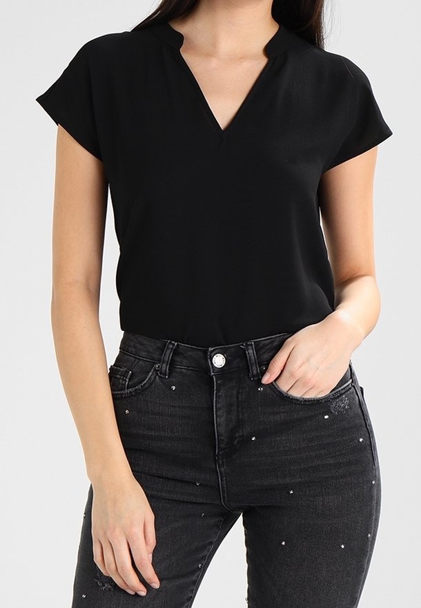 Haut noir à manches courtes avec un décolleté en V ; fabriqué en tissu lisse ; associé à un jean noir taille haute avec des clous décoratifs.