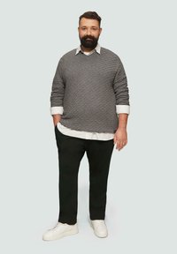 Grauer gesteppter Pullover über einem weißen Hemd mit Kragen, schwarze Hose und weiße Sneakers; bietet ein strukturiertes Material und eine entspannte Passform.