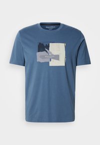 T-shirt de algodão azul com impressão em colagem na parte da frente, apresentando texturas e cores variadas. Design de mangas curtas e gola redonda.