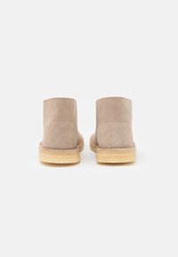 Botas de tobillo de ante color tan con punta redondeada, superficie texturizada y suela de goma ligera, que cuentan con acentos cosidos a lo largo del borde.