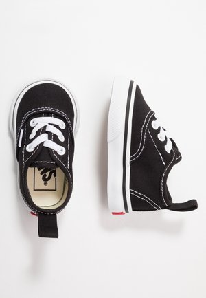 Schwarze Kindersneaker mit weißen Schnürsenkeln, weißen Gummi-Zehenschutzkappen und weißen Sohlen, von oben und von der Seite auf weißem Hintergrund gezeigt.