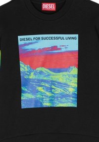 Felpa nera con un design grafico colorato che presenta montagne e la scritta "DIESEL PER UNA VITA DI SUCCESSO" in bold nero.