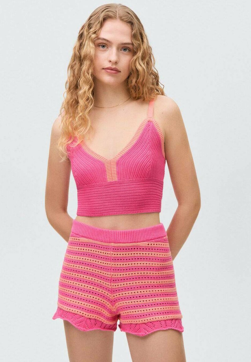 Ružový pletený crop top s výstrihom do V a zodpovedajúcimi šortkami s horizontálnymi pruhmi a scalloped okrajmi. Mäkká textura a priliehavý strih.