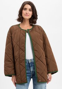 Smeđa podstavljena jakna s okruglim izrezom, zelenim obrubom i kopčanjem na dugmad. Ima široke rukave i meku, teksturiranu završnicu.