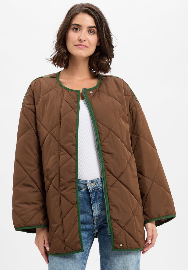 Smeđa podstavljena jakna s okruglim izrezom, zelenim obrubom i kopčanjem na dugmad. Ima široke rukave i meku, teksturiranu završnicu.