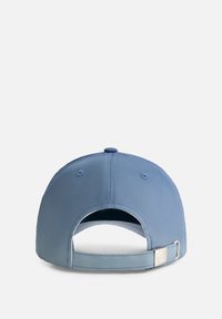 Lichtblauwe baseballpet met een gebogen klep, verstelbare strap aan de achterkant en een onderscheidend metalen accent. Soepele textuur en klassieke vorm.