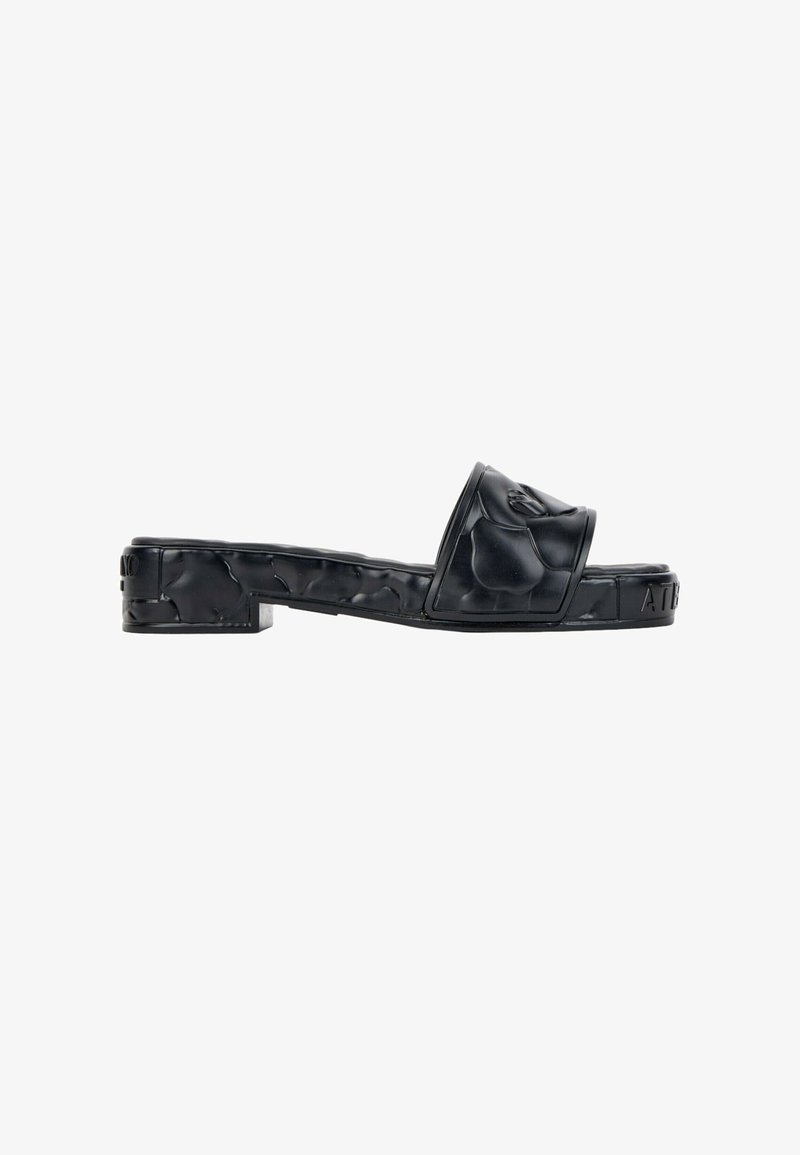 Sandale noire style mule avec une semelle plateforme texturée et une large bride présentant un motif floral en relief.