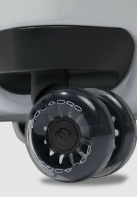 Rueda de plástico negro con cubierta transparente que presenta un logo blanco y radios. Adyacente a un cuerpo gris redondeado con acabado mate.