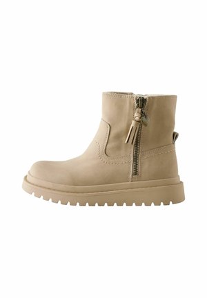 Beiger Knöchelstiefel mit dicker Sohle, seitlichem Reißverschluss mit Quaste und Herz-Anhänger sowie Zuglasche hinten, von der Außenseite gezeigt.