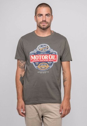T-shirt en coton gris avec un grand graphique rétro "Huile de moteur" en rouge et bleu, comprenant du texte et des logos, manches courtes standards et col rond.