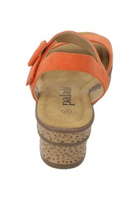 Sandalia naranja con correas anchas, botón de acento circular y tacón de cuña estilo corcho marrón con detalles perforados. Interior de planta suave.