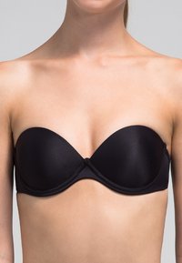 Sujetador negro sin tirantes con tela lisa, copas moldeadas y cierre en el centro delantero. Presenta un diseño sin costuras para un ajuste discreto.