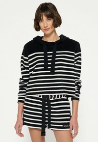 Sudadera a rayas en blanco y negro con cord�ón y mangas largas, combinada con pantalones cortos a juego que cuentan con una cintura elástica y un lazo.