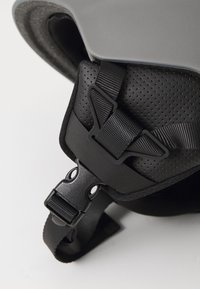 Black helmet interior featuring textured padding, an adjustable buckle, and straps for secure fit. Smooth, glossy exterior with a sleek design.
