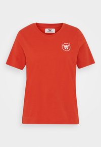 Červené bavlněné tričko s krátkým rukávem, kulatým výstřihem a bílým kruhovým logem na hrudi. Hladká textura, ležérní střih.