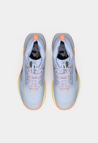 Zapatillas deportivas de color azul claro con acentos naranjas, parte superior de malla texturizada y suela de goma. Cuentan con cordones y un diseño de tobillo que brinda soporte.