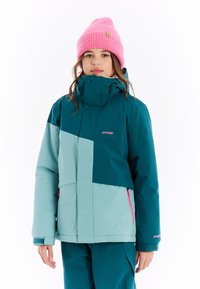 Teal- und mintgrüne isolierte Jacke mit hochgeschlossenem Kragen, mit Reißverschlusstaschen und pinken Akzenten; kombiniert mit einer pinken Strickmütze.