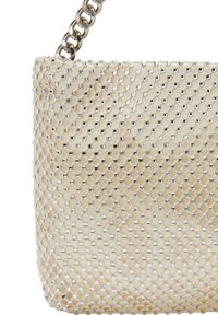 Veskes med kædeaccent, der har et beige sekskantet netdesign med shiny metalliske elementer, som skaber en tekstureret overflade og struktureret form.