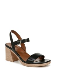 Sandal con tacco a blocco in pelle nera, con punta aperta e cinturino alla caviglia regolabile, che presenta una base con texture legno chiaro e una tomaia liscia.