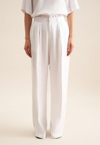 Witte linnen broek met een hoge taille, plooien en een losse, rechte pasvorm. Gladde textuur en minimalistische stijl.