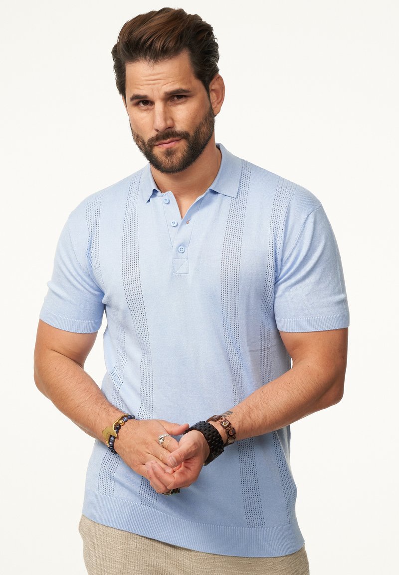 Helles blaues Poloshirt mit kurzen Ärmeln aus weichem Stoff, das ein strukturiertes vertikales Streifenmuster und eine Knopfleiste mit drei Knöpfen aufweist.