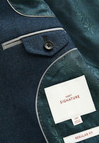 Marineblauer Stoffblazer mit einem gemusterten grünen Futter, verfügt über eine geknöpfte Tasche, graue Paspelierung und ein Etikett, das Marke und Größe angibt.