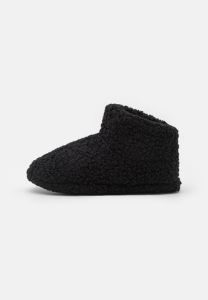 Schwarzer, flauschiger Knöchelstiefel aus strukturiertem Stoff. Verfügt über eine abgerundete Zehenpartie und ein weiches, gepolstertes Innenleben für Komfort. Keine sichtbaren Beschläge.