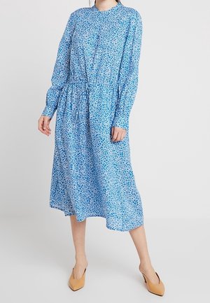 Abito lungo blu a maniche lunghe con dettaglio nodo in vita, caratterizzato da un piccolo motivo floreale e una silhouette morbida e fluida.