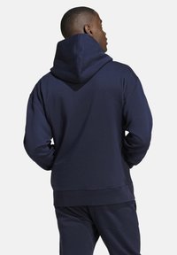 Felpa blu navy con un ampio cappuccio regolabile. Realizzata in morbido cotone, presenta una vestibilità comoda e polsini e orlo a costine.