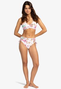 Ensemble de bikini avec un motif floral rose et blanc, comprenant un haut ajusté et un bas taille haute, conçu avec des liens latéraux réglables.
